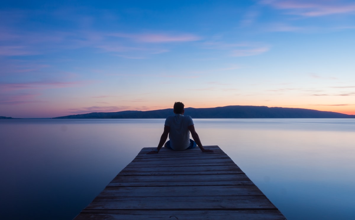 Persona en calma frente a un lago al atardecer